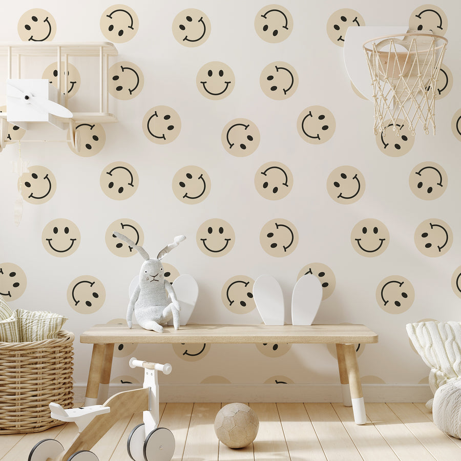 Ett lekrum för barn med en ljus bänk och leksaker, med tapeten 'Diane', en retrotapet med upprepande smileyansikten i mjukt pastellgult med svarta ansiktsdetaljer mot en ljust krämvit bakgrund.