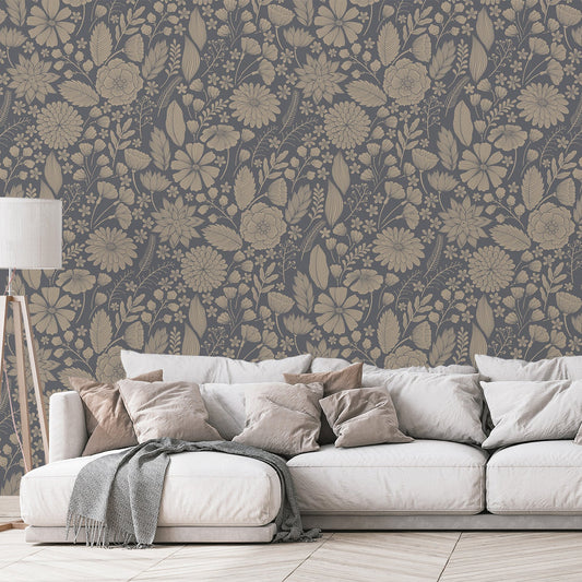 Ett vardagsrum med en beige soffa full av kuddar och en lampa, med tapeten 'Jessamine', en blå botanisk tapet med ömtåliga blommor, lummiga växter och fina botaniska illustrationer mot en mörkt blågrå bakgrund i ett upprepande mönster.