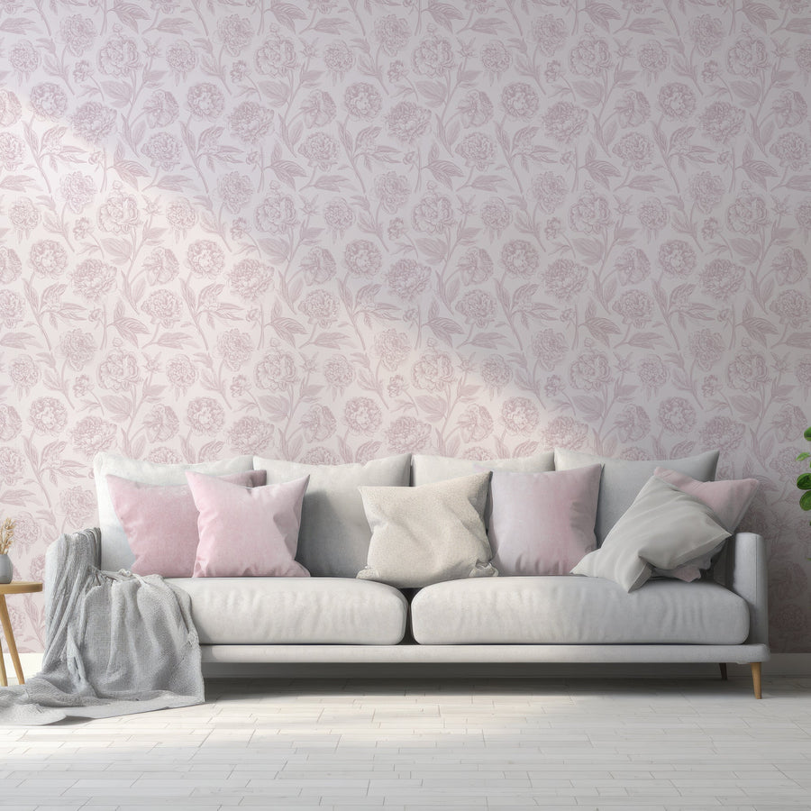 Ett vardagsrum med en soffa full av kuddar och tapeten Paisley, en ljusrosa tapet med mörkrosa pioner i vintagestil och lummiga botaniska detaljer i ett upprepande blommönster.
