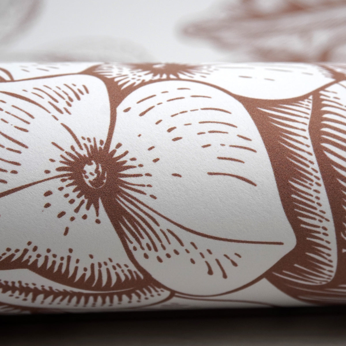 Närbild på ytan av självhäftande tapet från Peel & Paper, tryckt med en brun blomdesign.