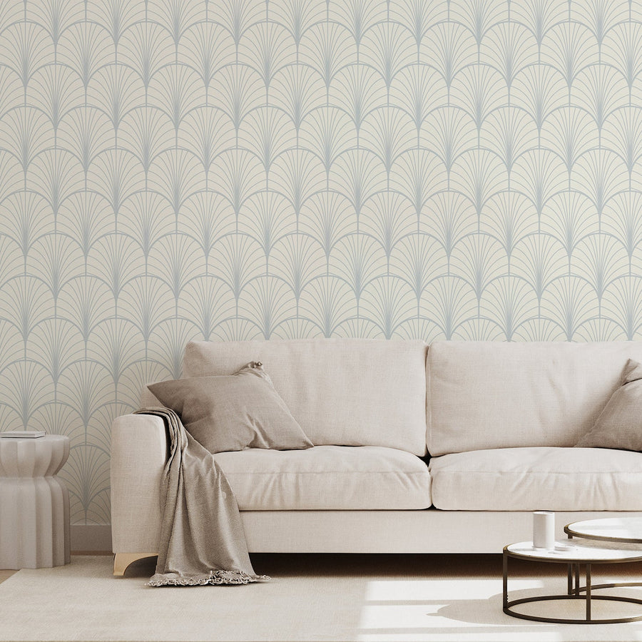 Ett vardagsrum med en beige tygsoffa och tapeten Theodora, med upprepande geometriska solfjädersformer i art deco-stil i ett elegant, vintageinspirerat mönster med en djärv, symmetrisk design.