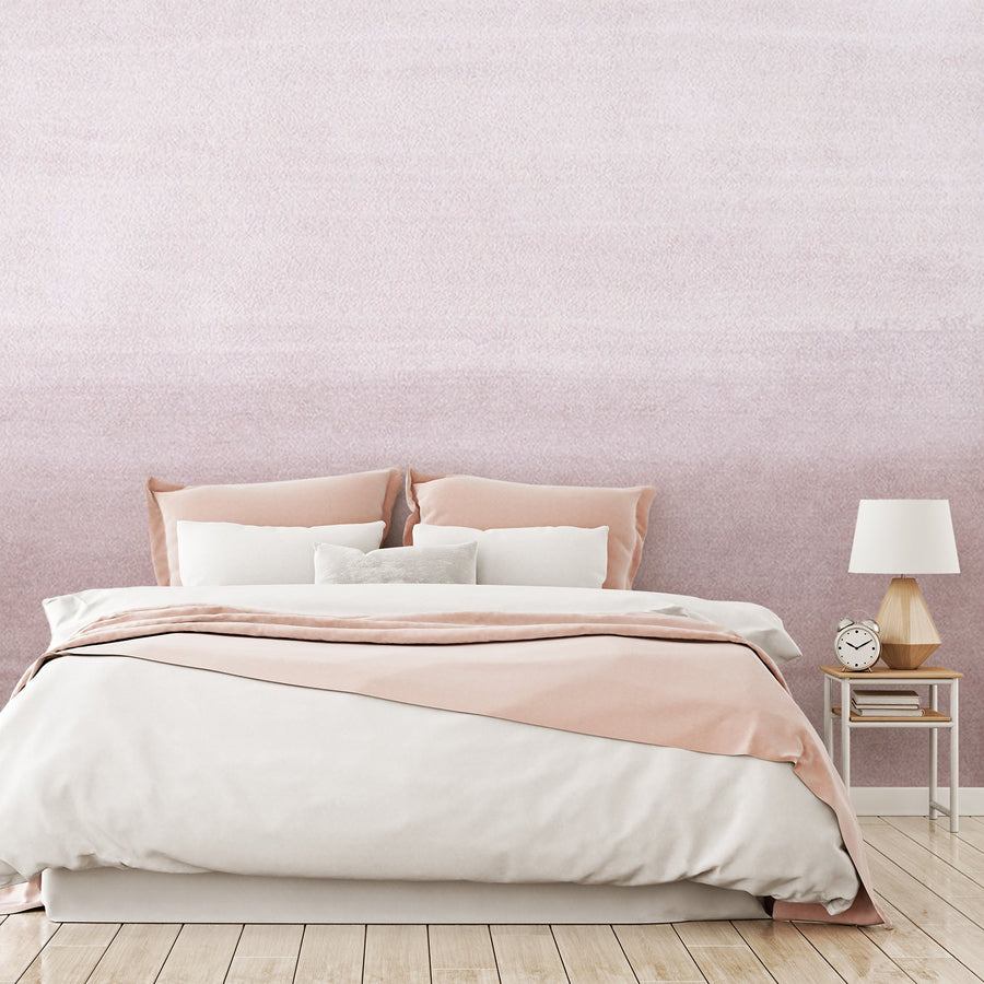 Ett sovrum med mjuka textilier och tapeten 'Clara Blush', en puderrosa tapet med en mjuk akvarelleffekt och en subtil ombrégradient som övergår mellan ljusare och mörkare rosa toner.