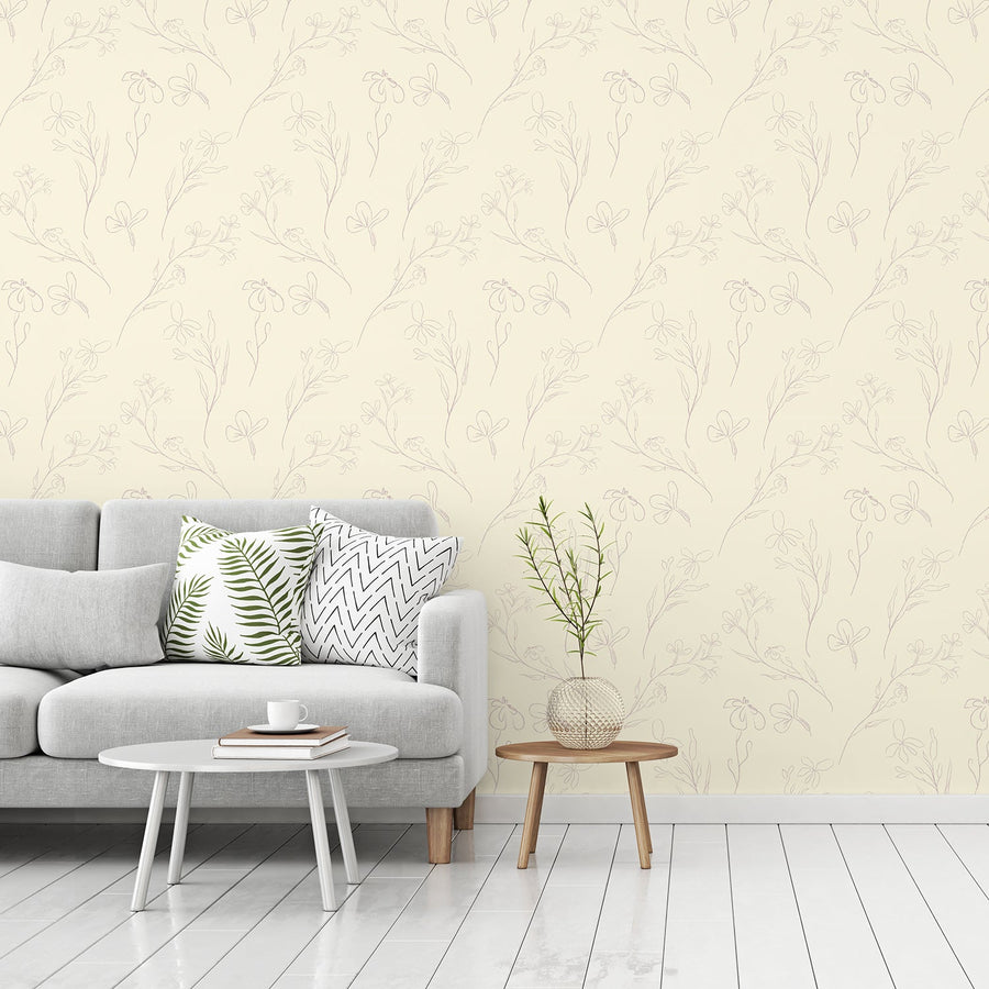 Ett vardagsrum med en grå soffa med två små bord bredvid, med tapeten 'Micaela', en modern tapet med fina konturillustrationer av blommor i ett enkelt upprepat botaniskt mönster i mjuka, dämpade toner.
