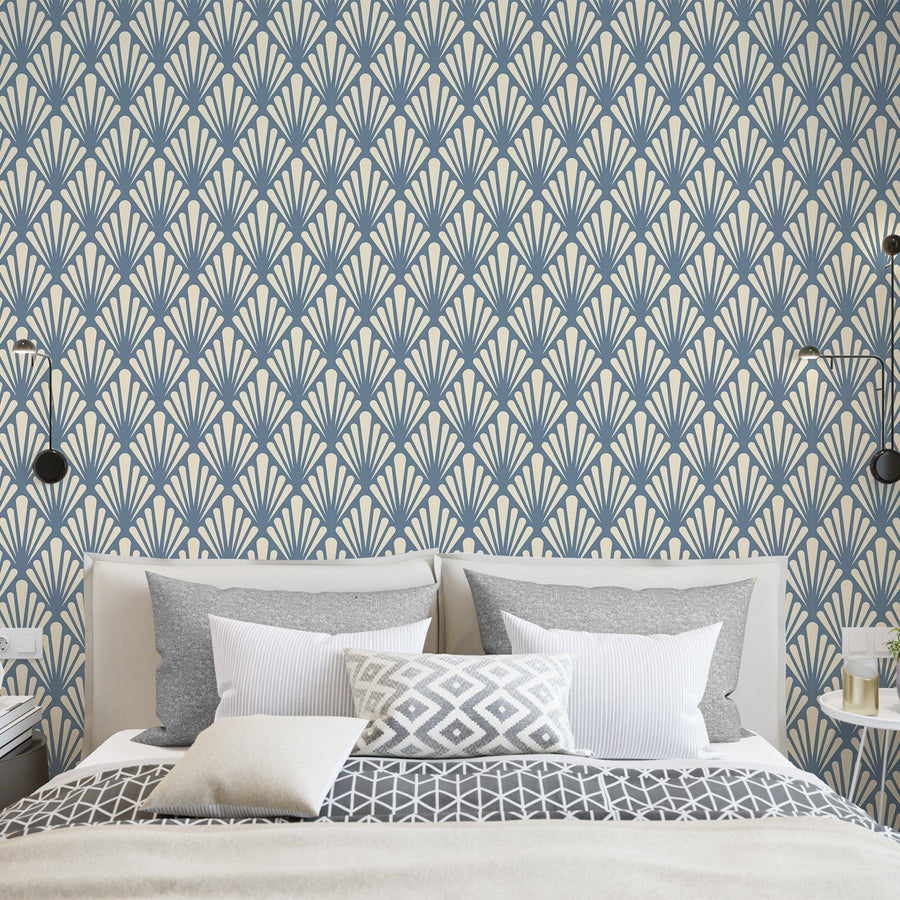 Ett sovrum med en säng med vita sängkläder, kuddar och lampor bredvid, med tapeten 'Virginia Slate', en skiffergrå art deco-tapet med stiliserade geometriska bladsolfjädrar och kantiga botaniska motiv i ett vintageinspirerat upprepat mönster.